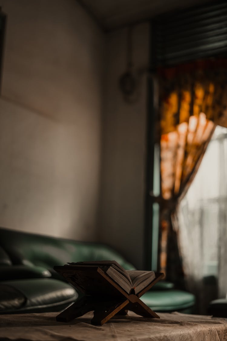 Open Book Lying On Stand On Table In Dark Living Room