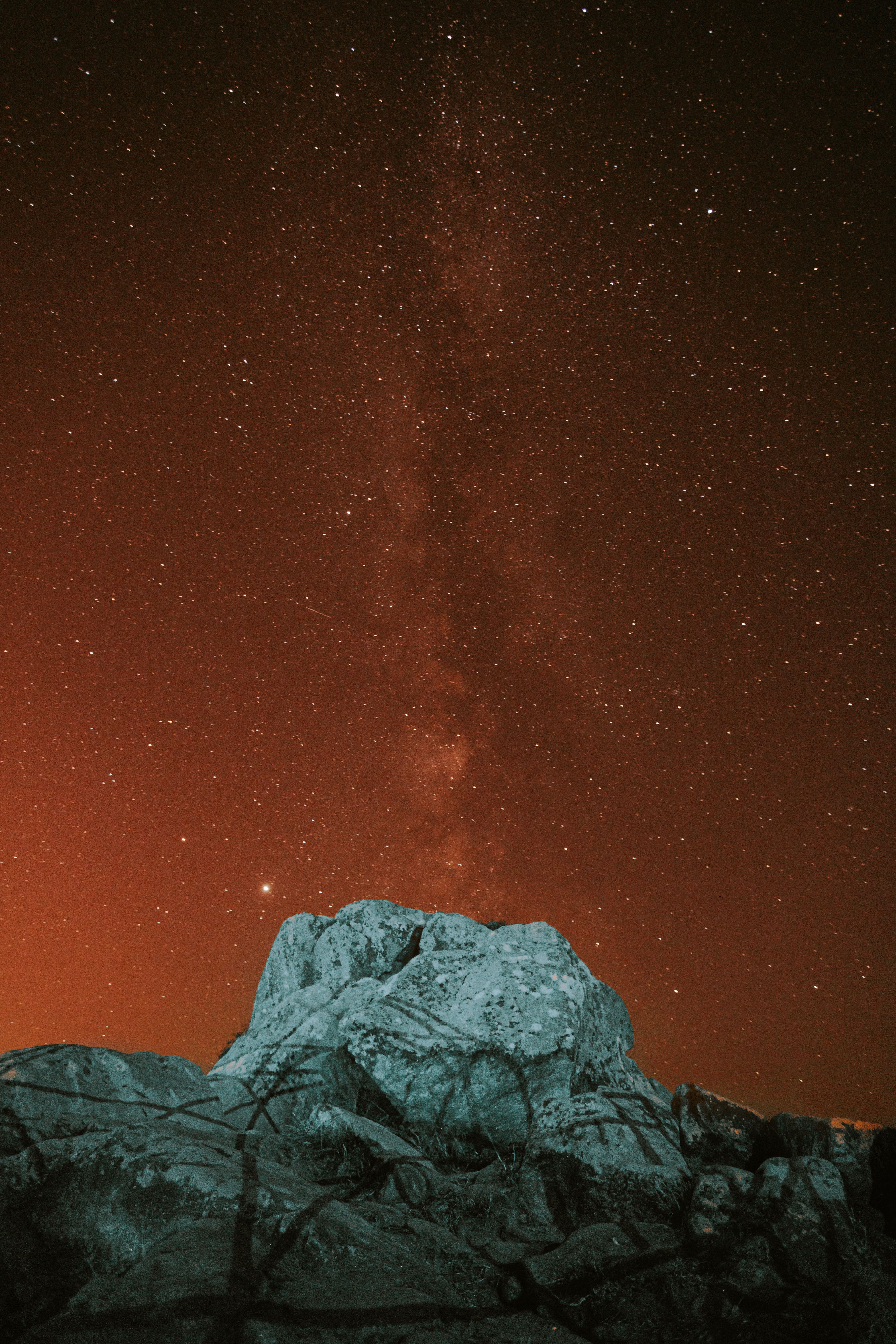 From below of stone structure located on top of cliff against starry sky glowing in night time in nature outside