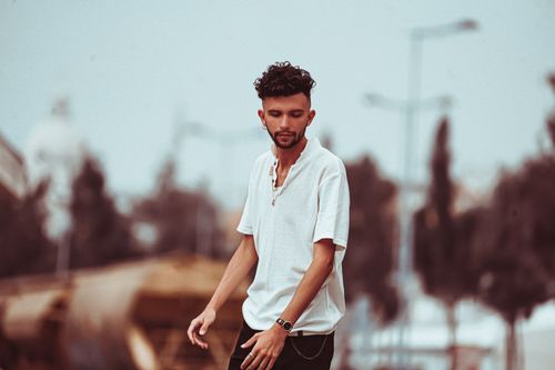 Free A fashionable young man in a white shirt poses in a blurred urban environment. Stock Photo