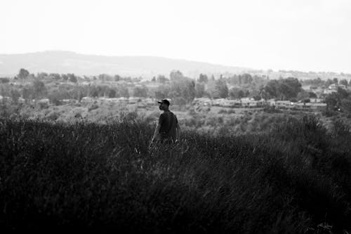 Free Grayscale Photo of Man Standing on Grass Field Stock Photo