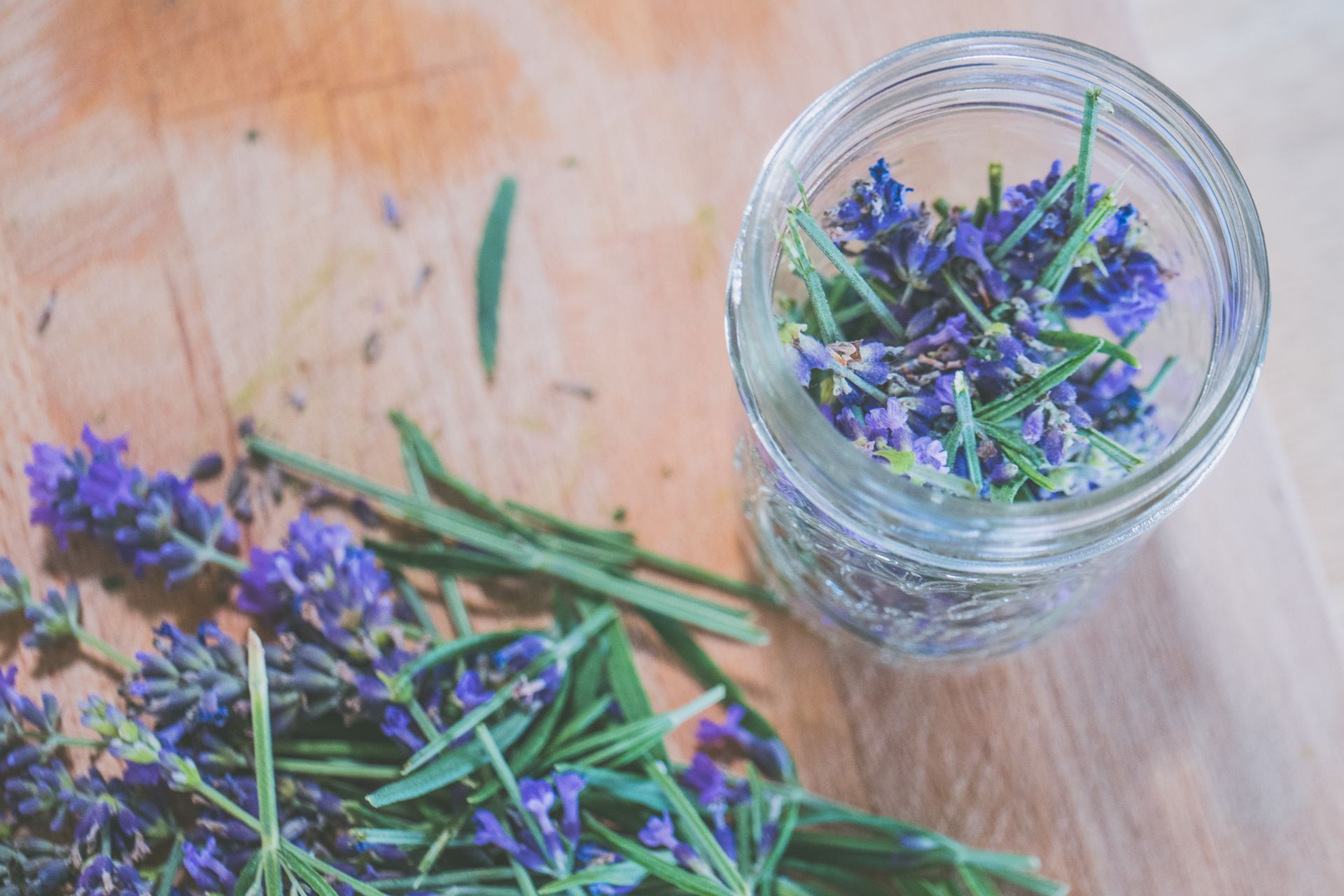 Top view of lavender and rosemary herbs in a glass jar for aromatherapy.