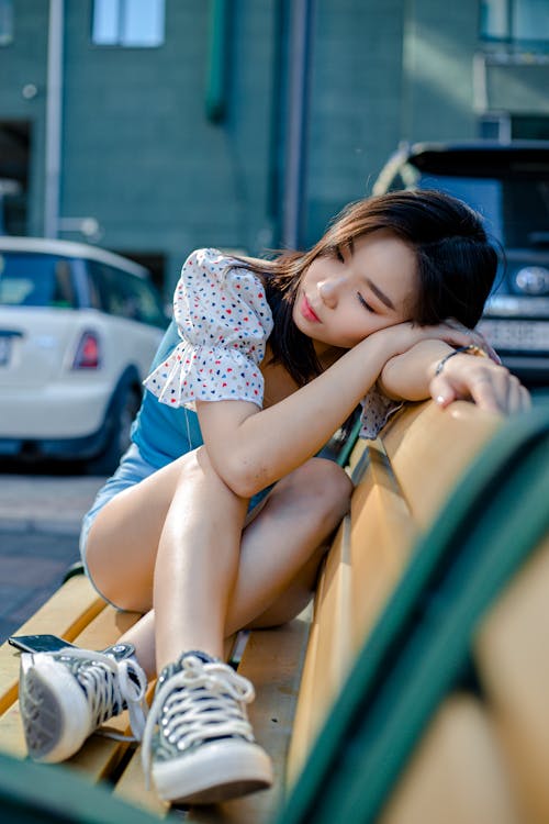 Dreamy Asian woman resting on bench in city