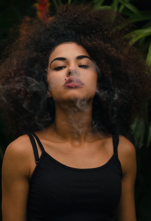 Free Calm ethnic woman exhaling light smoke Stock Photo
