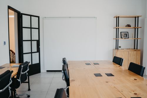 Free A clean and modern office space with wooden tables, chairs, and shelves, ideal for a creative work environment. Stock Photo