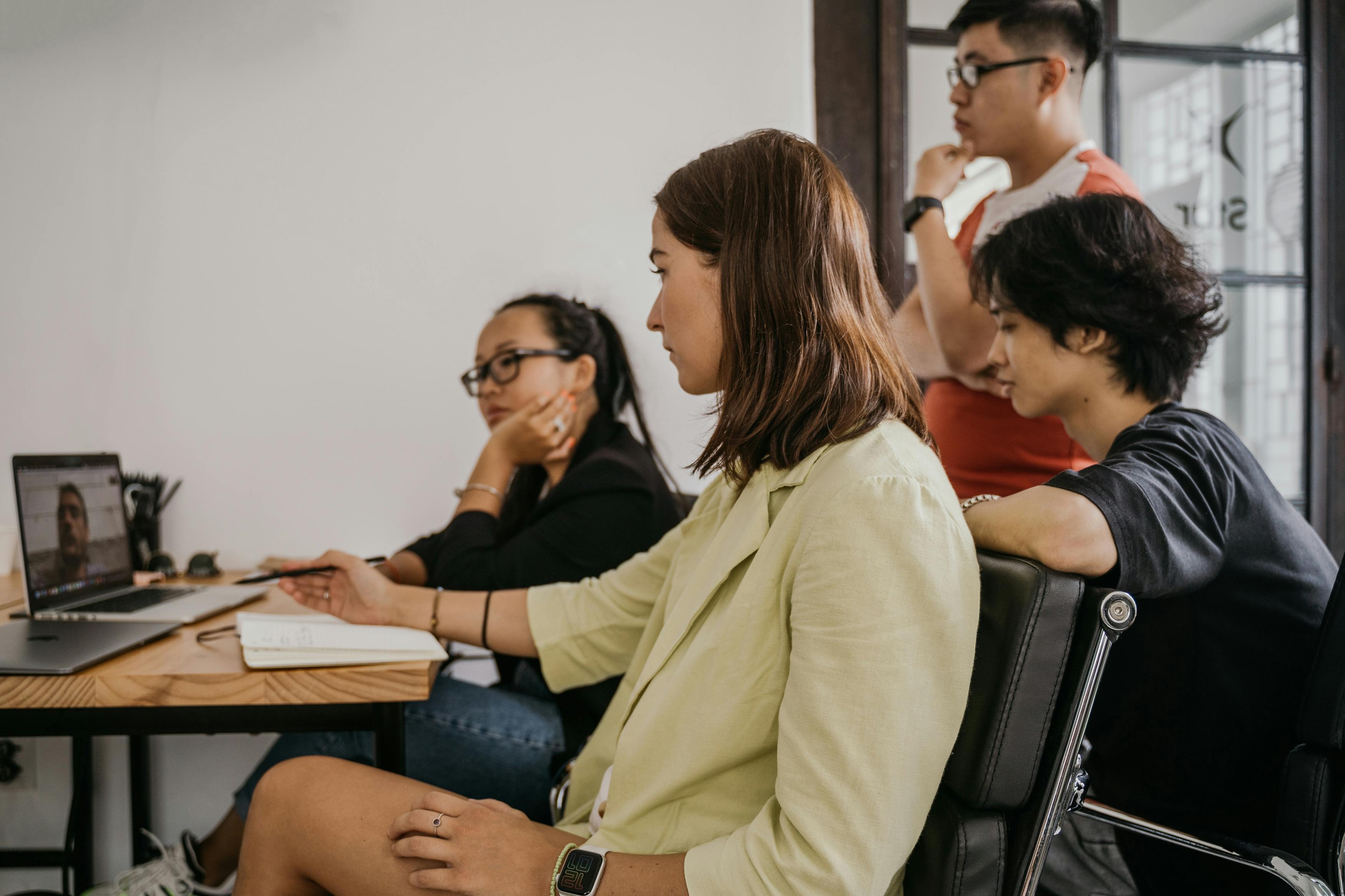 Four adults in a modern office engaged in a collaborative video conference.