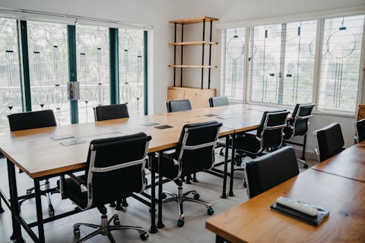 Spacious modern office conference room with black chairs and wooden tables.