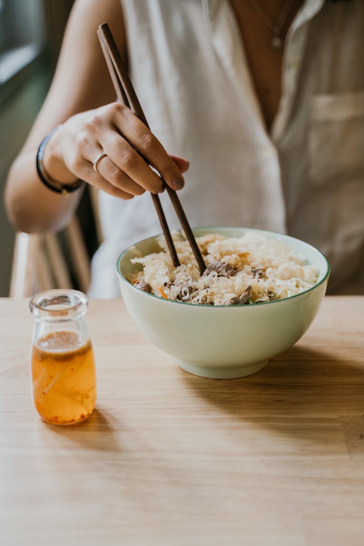 Close-up Of Woman Eating A Meal With Chopsticks