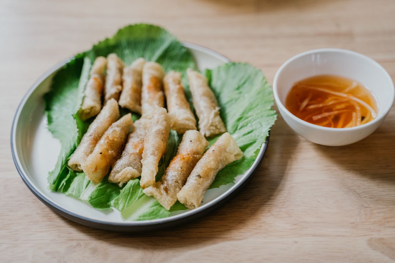 Món chiên vàng giòn bày trên lá rau xanh cùng chén nước chấm