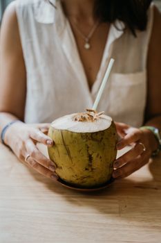 Close-up of fresh coconut with a straw being held by a person, capturing a tropical vibe.
