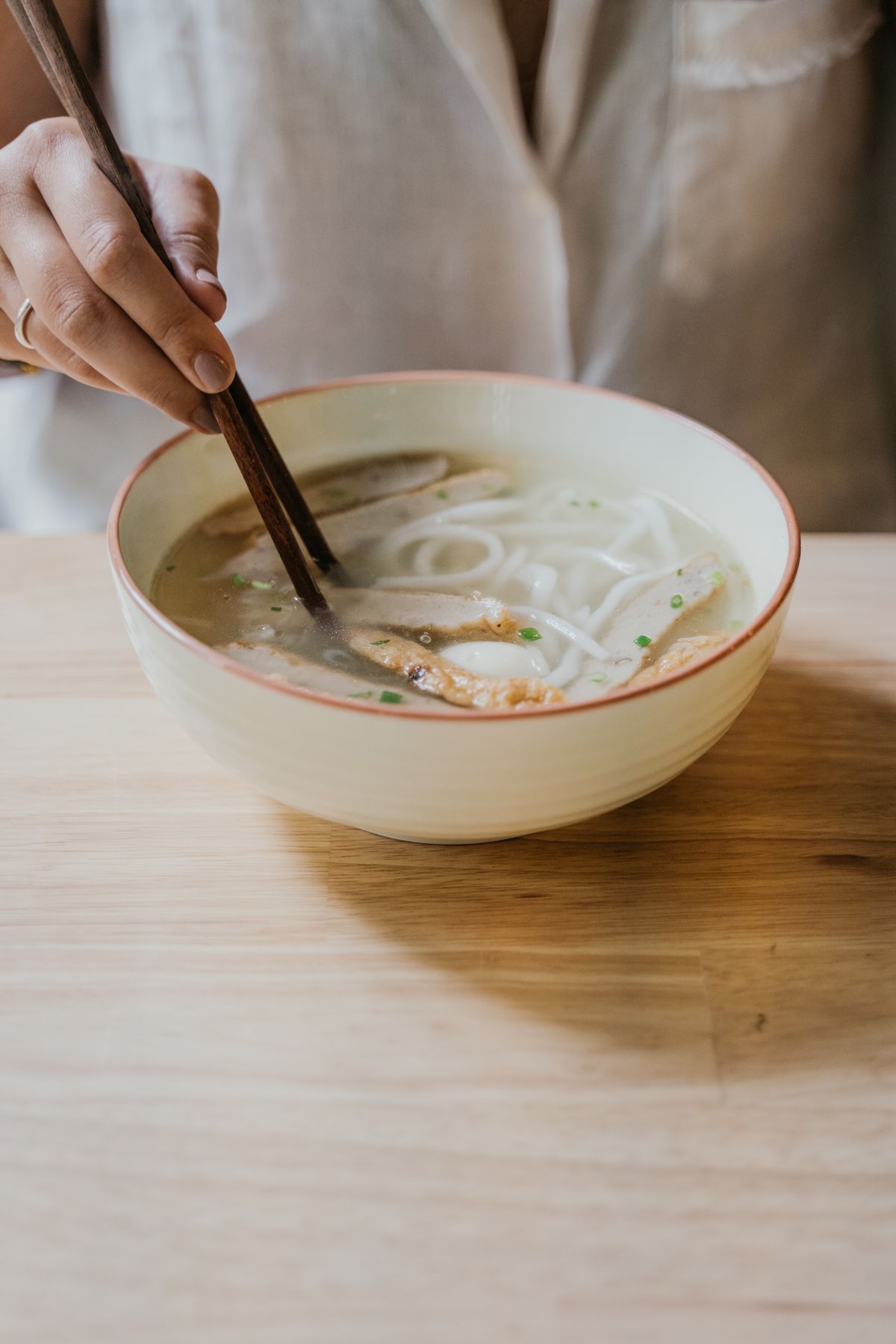 Close-up of chopsticks lifting noodles from a bowl of hot soup