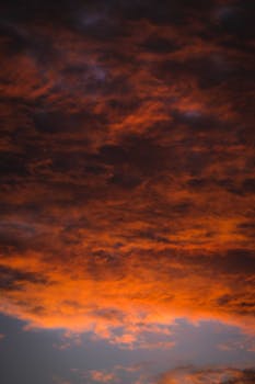From below or thick orange fluffy clouds floating in picturesque sky at sunset