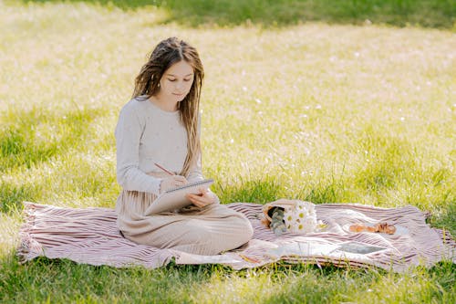 A Woman Sitting on a Blanket over Grass
