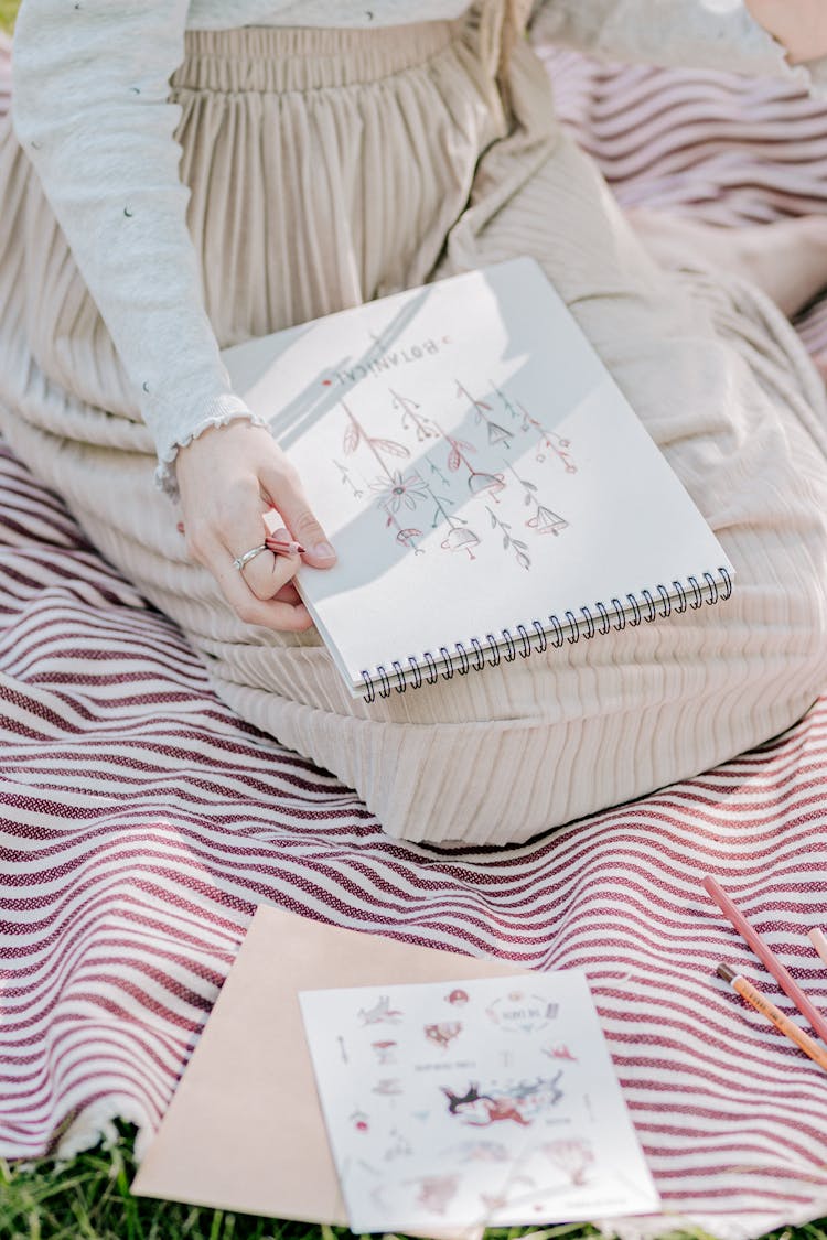 A Woman Drawing Plants On A Sketch Pad