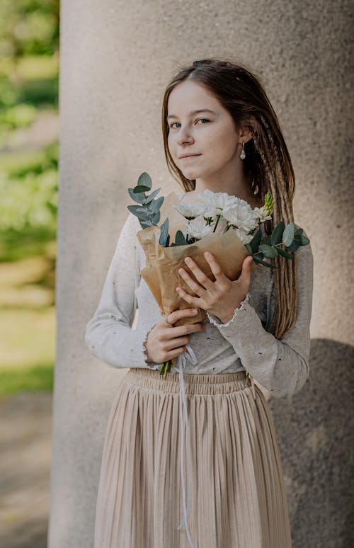 A Woman in Gray Sweater Holding a Bouquet of Flowers