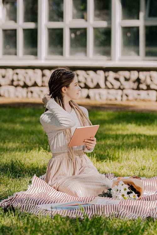 A Woman Holding an iPad while Relaxing in the Park
