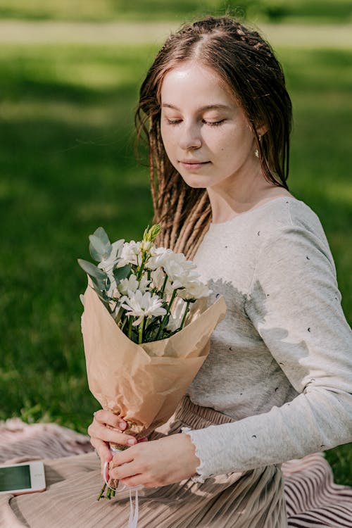 A Woman Relaxing in the Park Holding a Bouquet of Flowers 