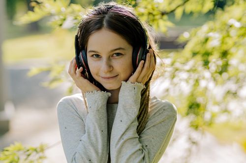 Free Smiling young woman listening to music outdoors with headphones, embracing a moment of relaxation. Stock Photo