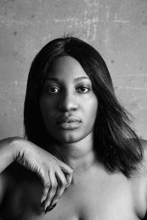 Black and white confident African American plump female looking at camera sitting against gray background