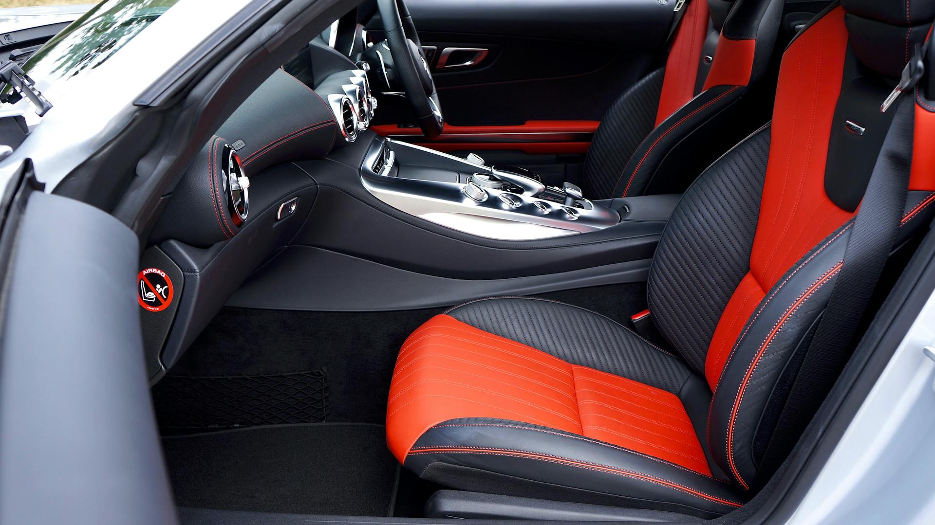 Sleek, modern car interior featuring red and black leather seats and advanced dashboard controls.