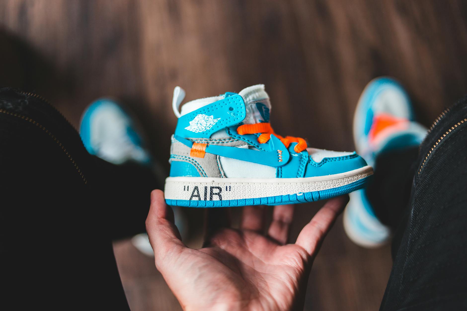 From above of crop anonymous person demonstrating modern comfortable bright children sneaker with ornament at home