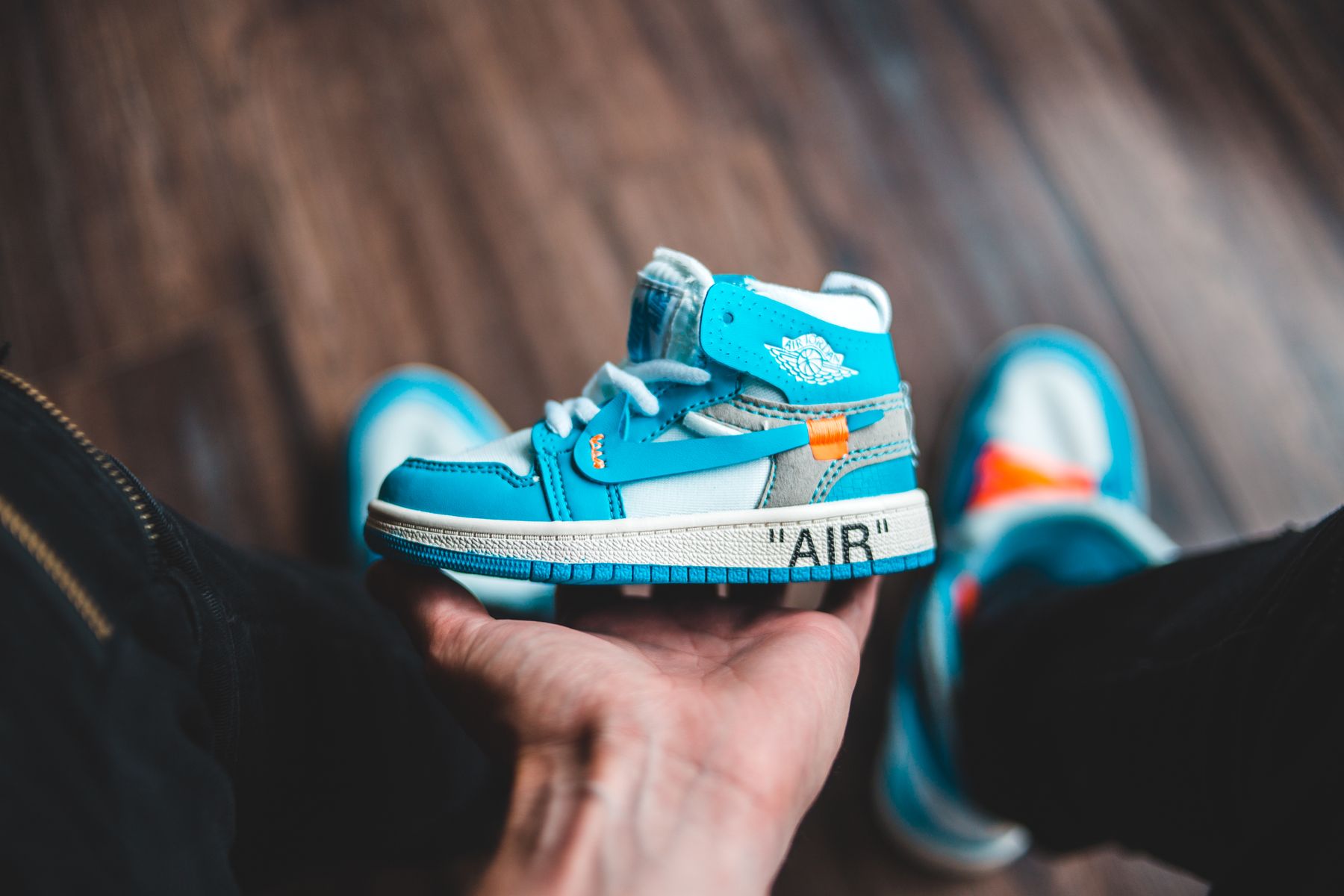 Vibrant blue kids sneaker held by an adult hand indoors