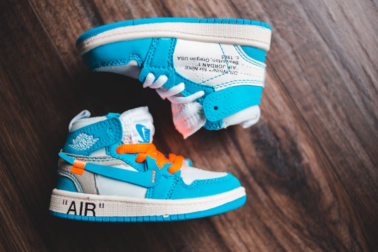 Pair Of Baby Sneakers On Wooden Floor