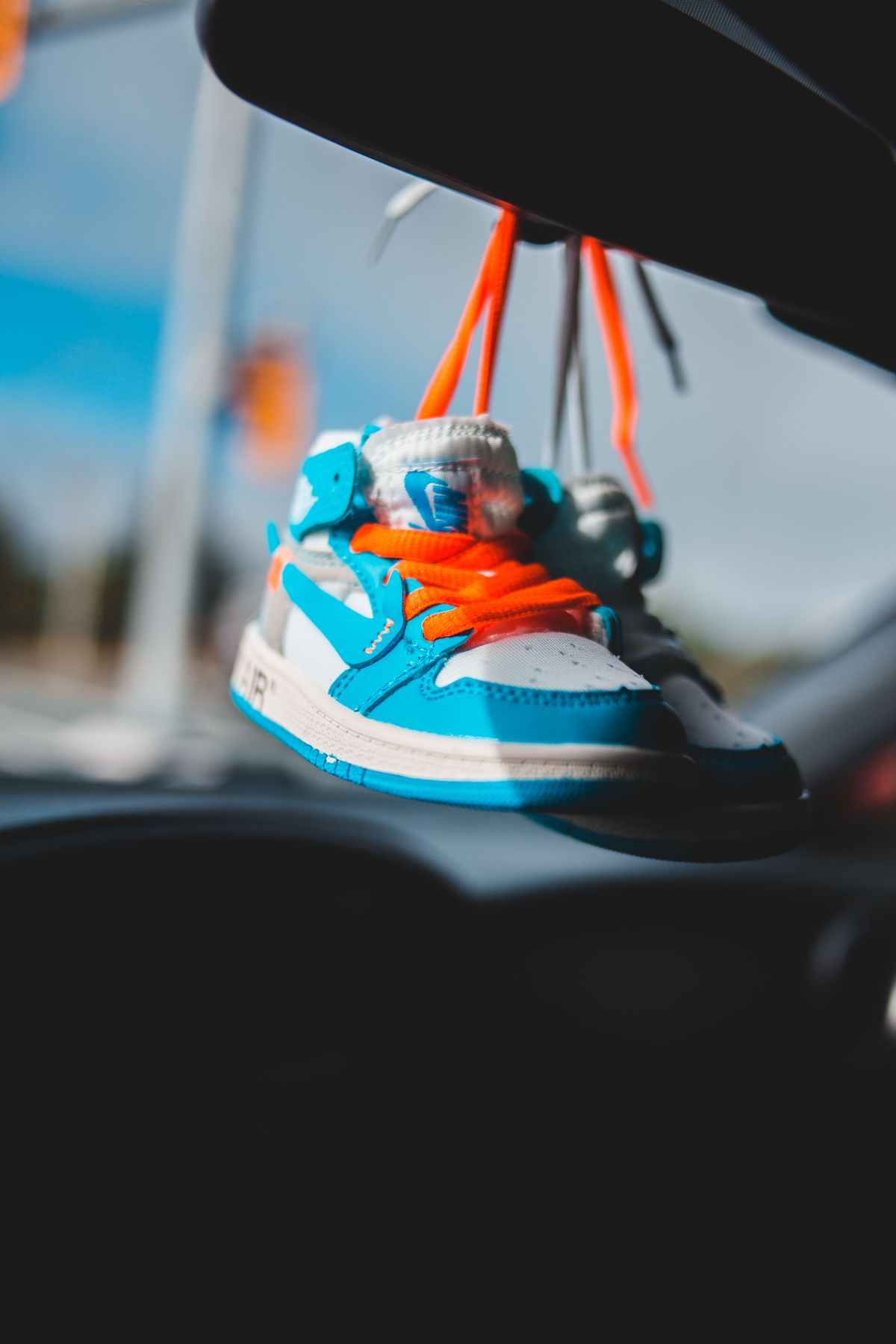 Kids sneakers hanging in a car during road trip games for kids
