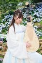 Woman in White Dress Playing Guitar