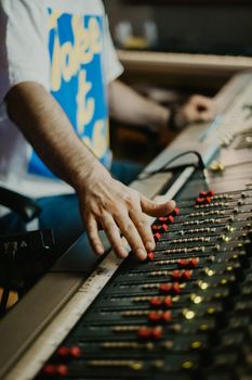 Sound engineer adjusting the mixing panel inside a recording studio.