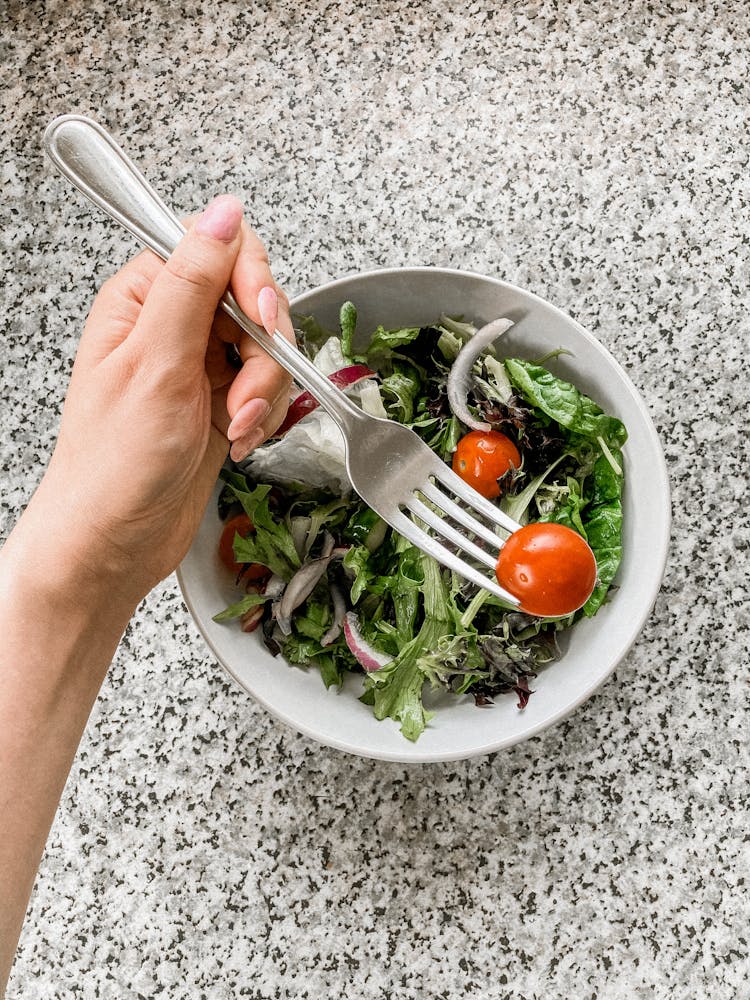 Person Eating Tomato From Salad