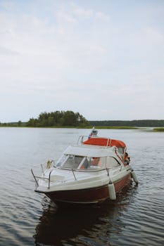 一艘白色的摩托艇静静地停泊在平静的湖面上，远处有树木