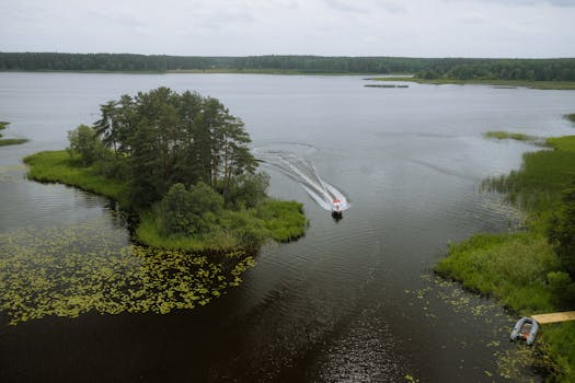 A serene aerial view of a boat navigating a lake in Tver Oblast, Russia, surrounded by lush greenery.