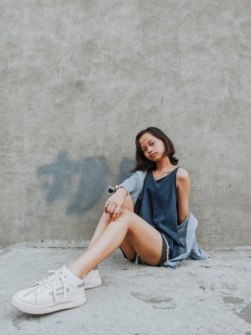 Young ethnic woman sitting against shabby concrete wall