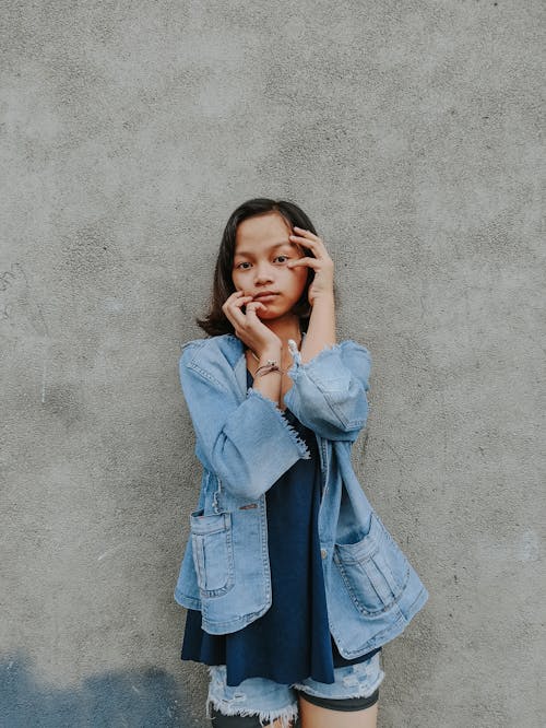 Serene ethnic woman touching face gently against shabby wall