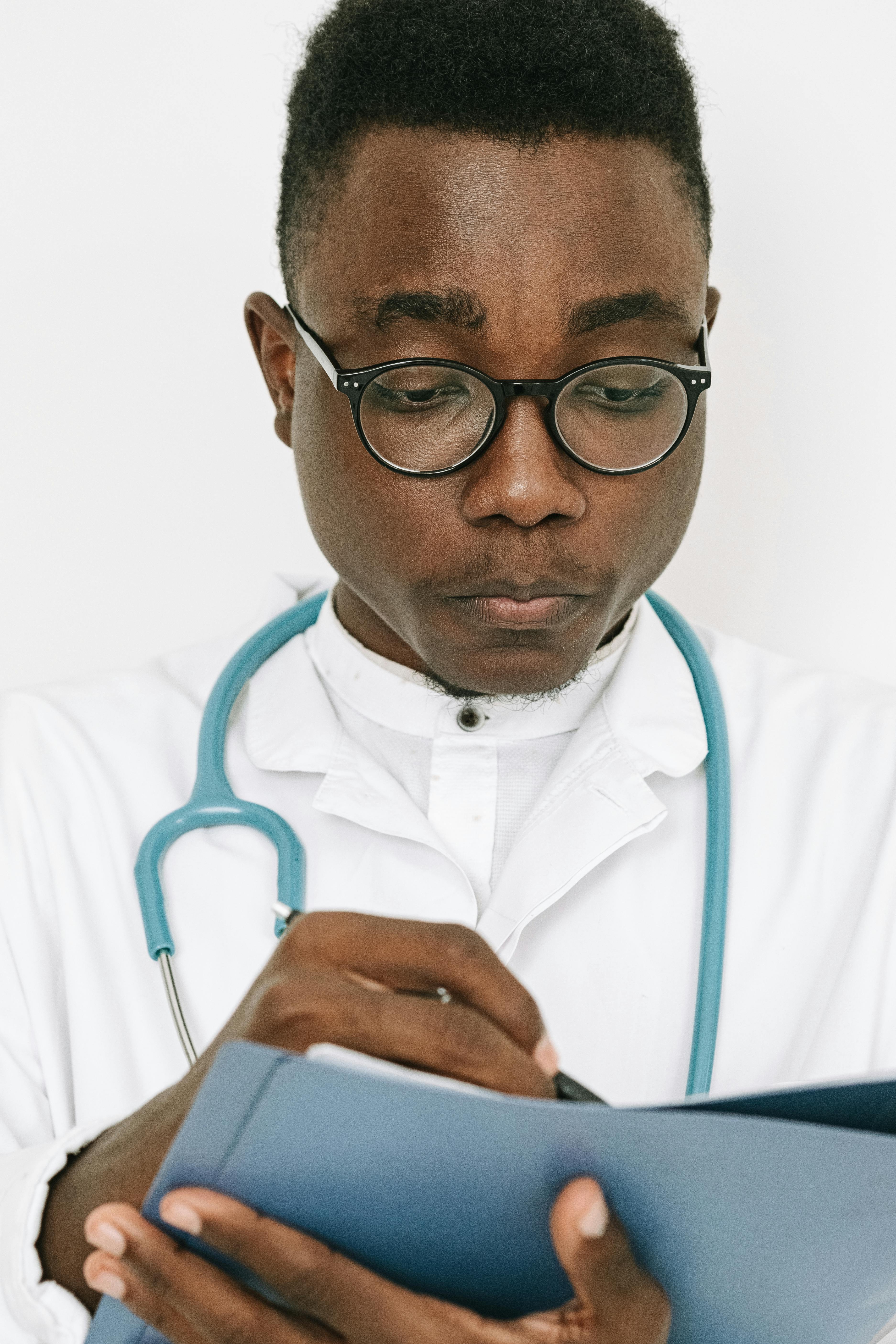 专注的男医生在室内用听诊器在剪贴板上写下笔记