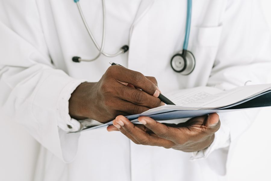 A doctor writing on a clipboard with a stethoscope nearby