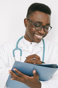 Friendly doctor with stethoscope writing on a chart in a bright room.