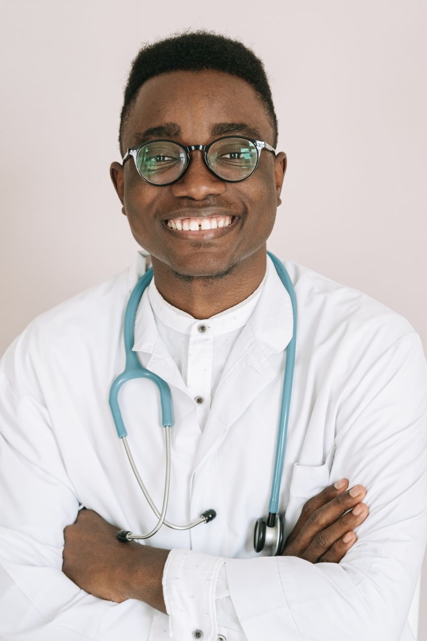 Dr. Daniel Okafor, rhinoplasty and breast surgeon, smiling in a white coat