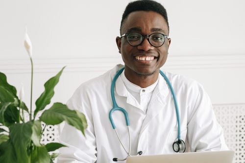 Free Cheerful young doctor in uniform with stethoscope and eyeglasses, exuding professionalism. Stock Photo