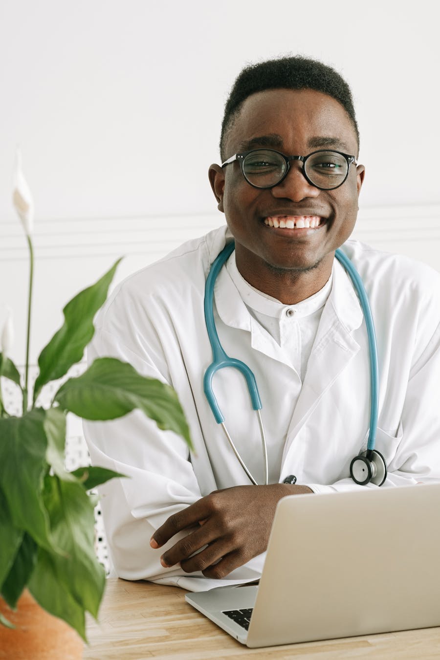 African doctor smiling with a laptop in a bright clinic