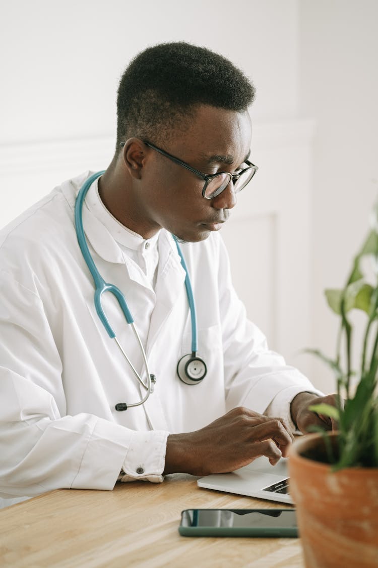 A Doctor Typing On His Laptop