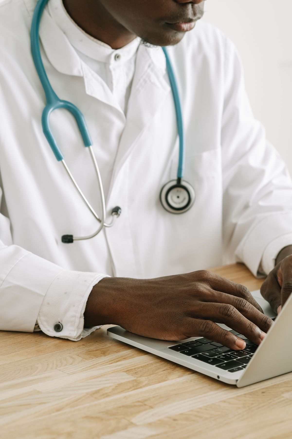 Doctor in a white coat typing on a laptop representing the licensed medical backing behind GLP-1 affiliate programs