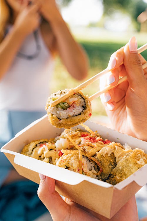 Person Holding Sushi with Chopsticks