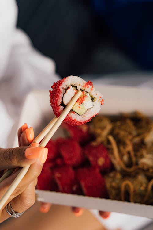 Close Up Photo of a Sushi on Chopsticks