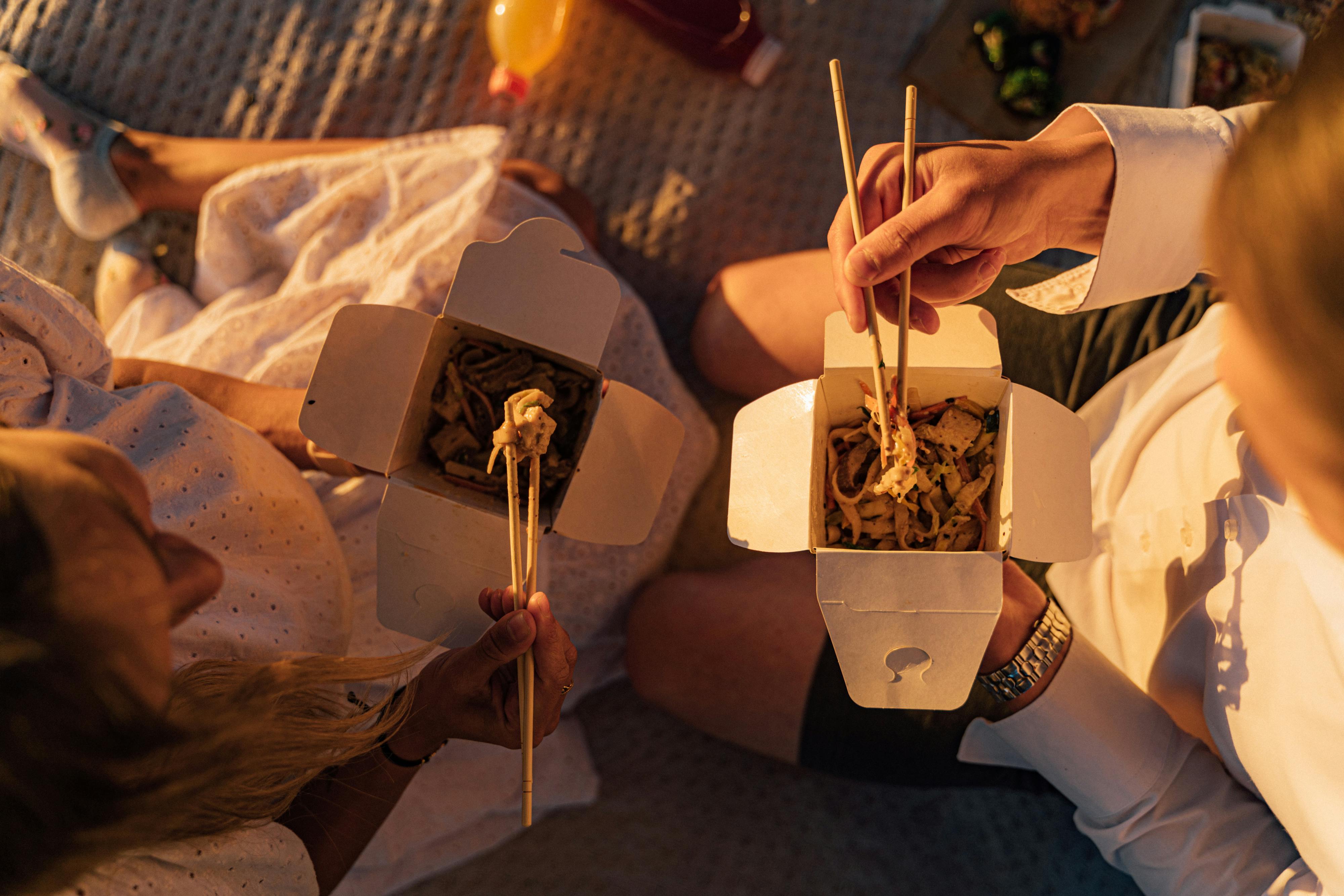 person holding brown wooden chopsticks while eating noodles