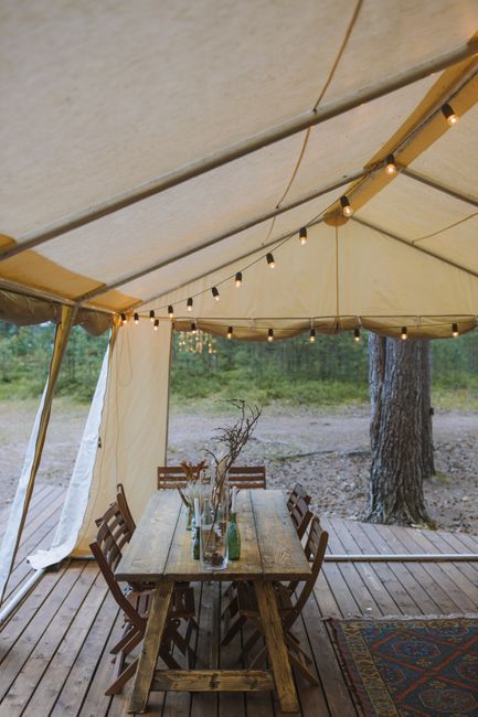 A cozy glamping tent with string lights beside a calm Midwest lake at sunset