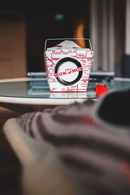 Free Small carton box with delicious wok food placed on small round glass table in light room Stock Photo