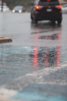 Blurred car reflections on a rainy city street, capturing urban traffic and weather.