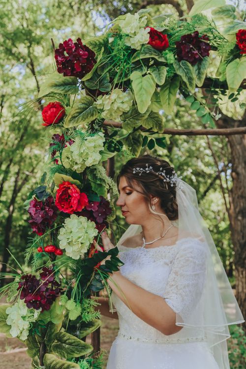Free Side view of young woman in stylish wedding dress with flowers standing with closed eyes in garden Stock Photo