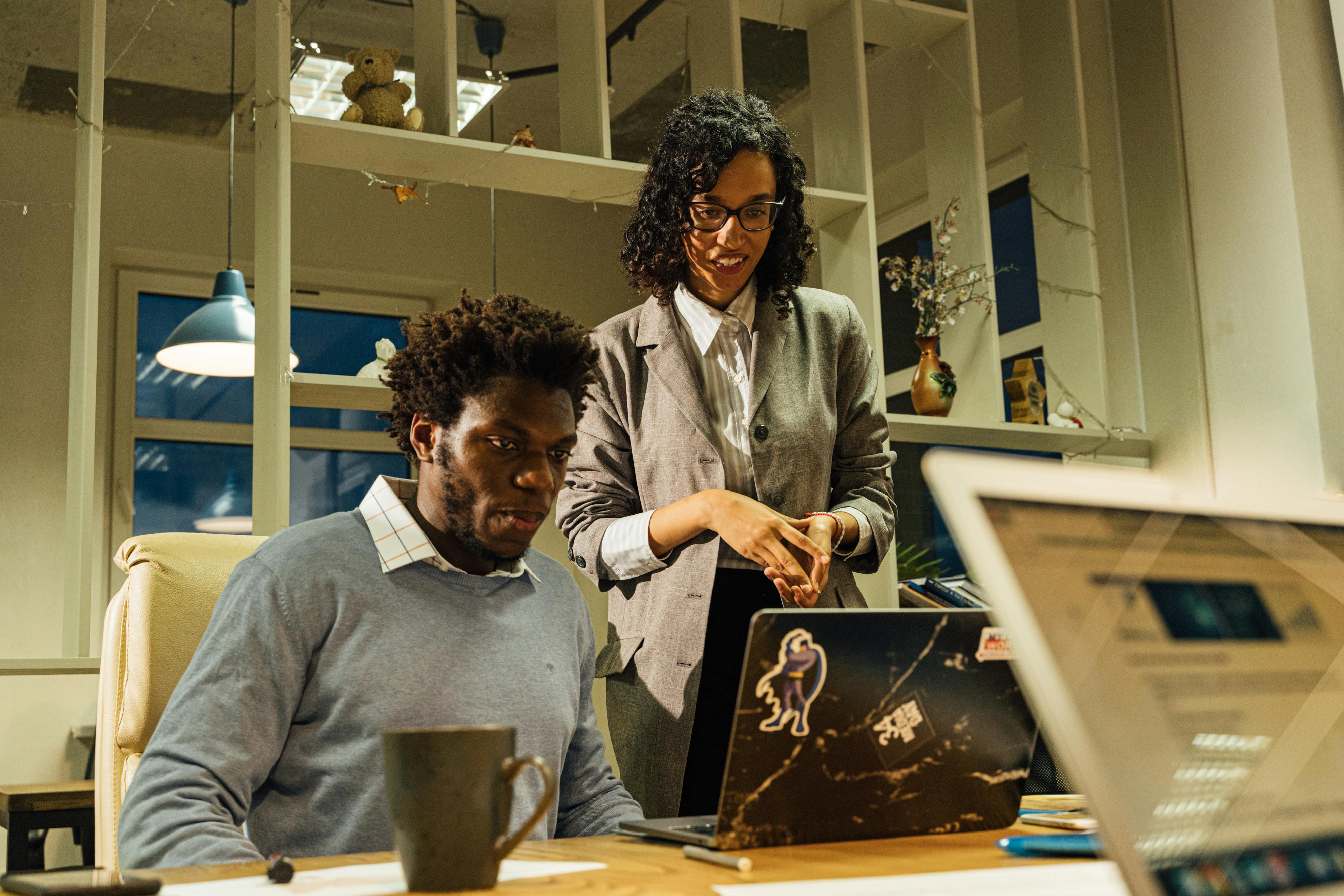 在现代化的办公室里，两名同事一起工作，用笔记本电脑分享想法